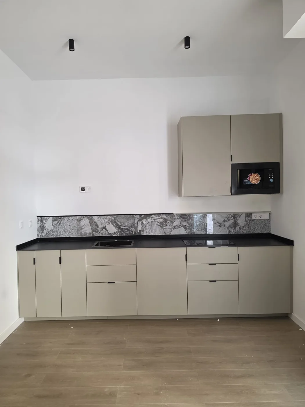 Cocina recta montada con encimera negra y frente de mármol en Murcia
